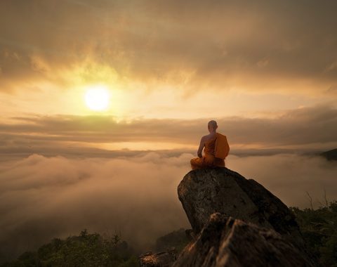 Buddhist monk in meditation at beautiful sunset or sunrise backg Buddhist monk in meditation at beautiful sunset or sunrise background on high mountain